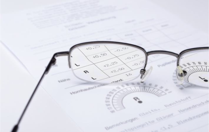 A pair of glasses sits on top of a printed out prescription paper.