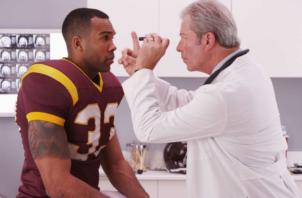 A football player gets his eyes checked a doctor after a concussion.