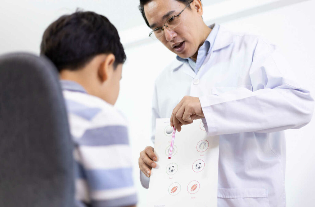 A male eye doctor is  holding a paper with images, his making a total vision therapy assessment on his patient.