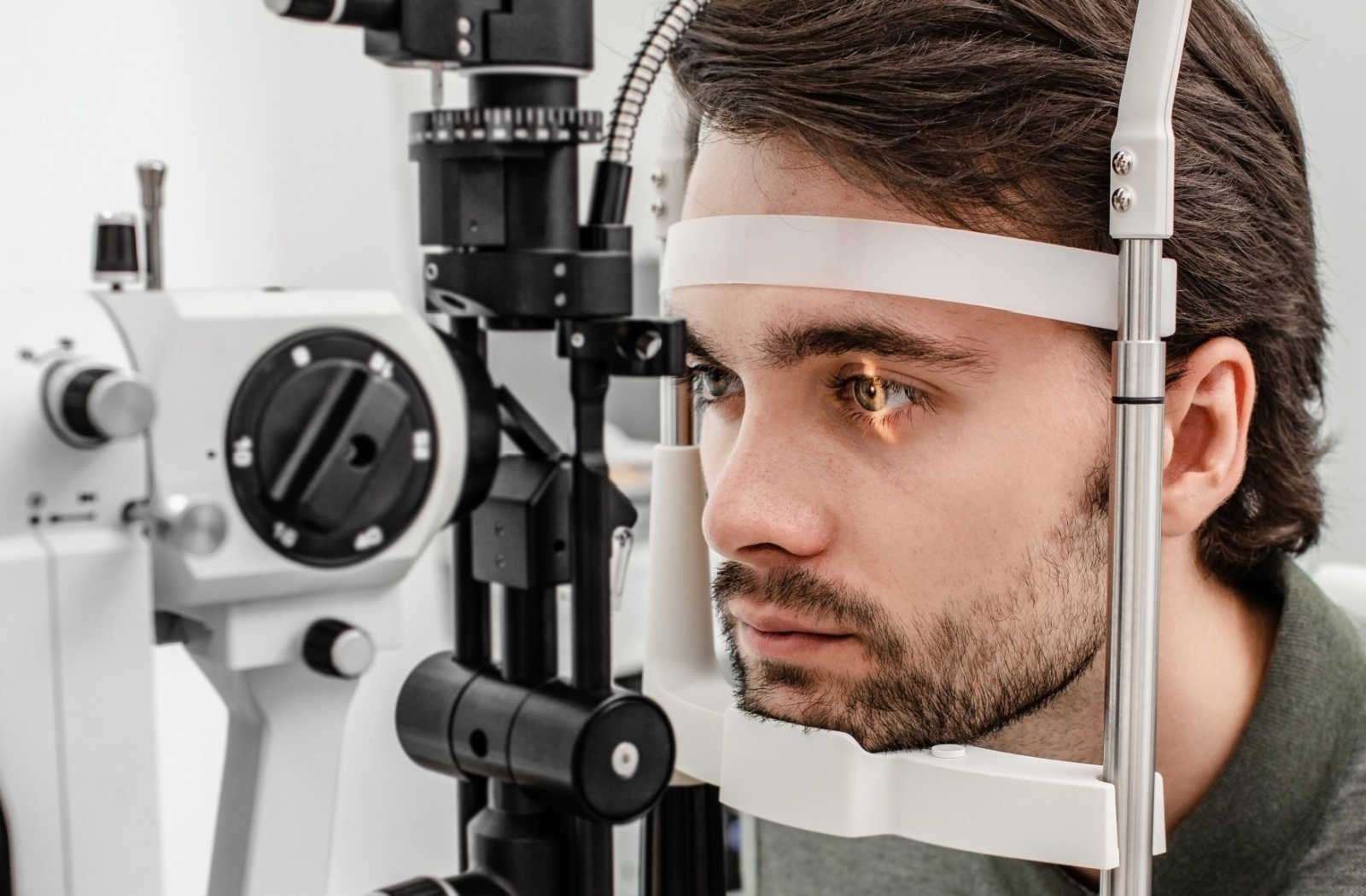 A man sitting in an ophthalmologist's office looking into a machine that tests his vision.