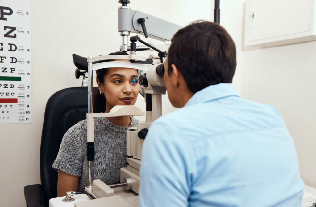 A young woman with her optometrist performing an eye exam using a medical device to detect eye problems.