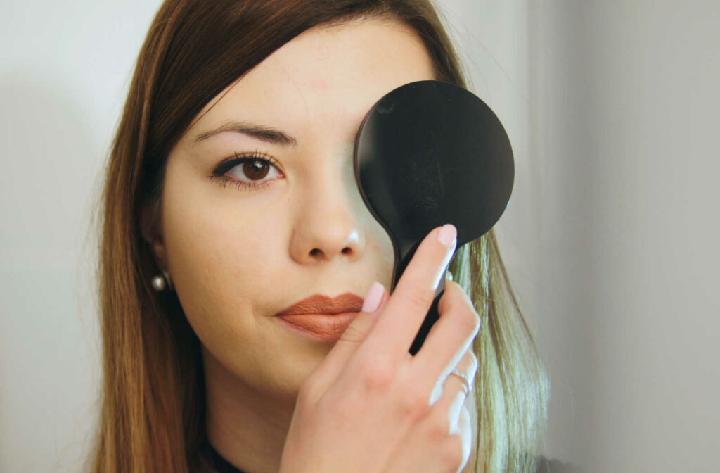 A woman covering her left eye with a medical instrument to check her vision.