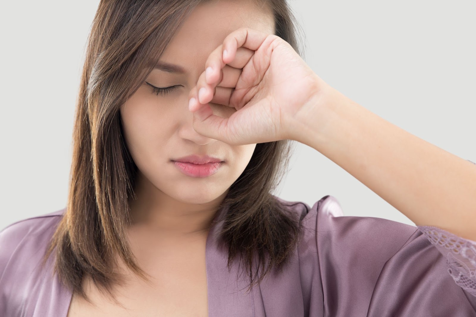 Woman rubbing her left eye.