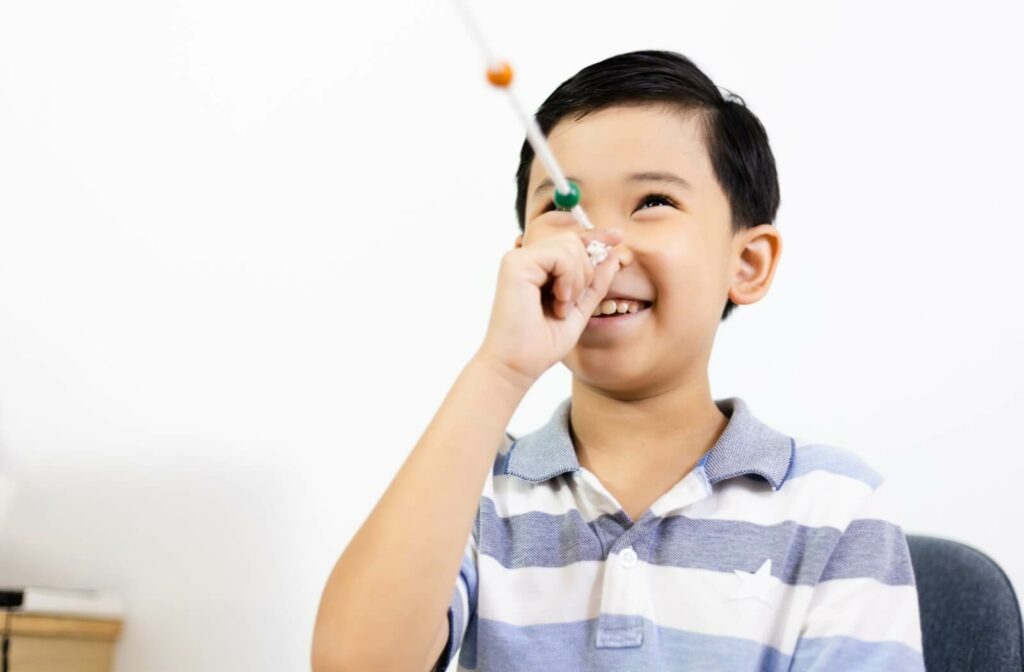 A child smiling while doing a Brock string exercise during vision therapy for convergence insufficiency.