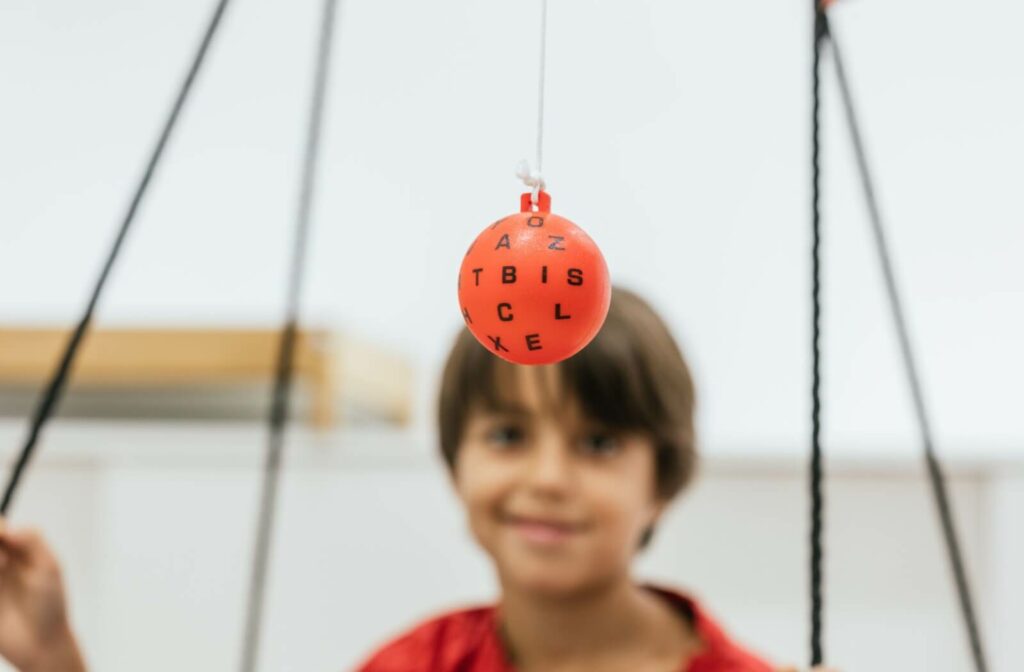 a child uses a Marsden ball while undergoing vision therapy to improve eye movement and tracking