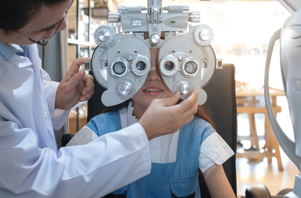 An optometrist uses a phoropter to assess a young patient's eyesight during a comprehensive children's eye exam.